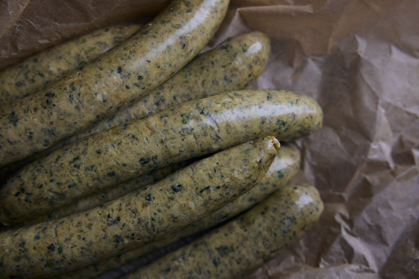 Raw green harissa chicken sausages on brown butcher paper