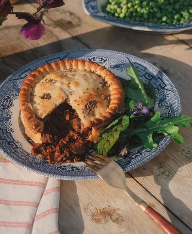Grass-fed beef steak, mushroom and ale pie on a blue willow plate with greens