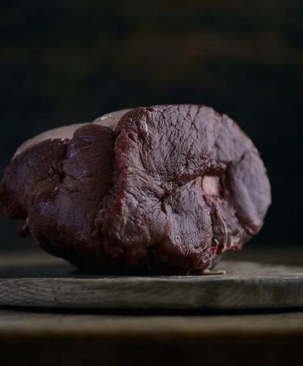 Bone-in wild venison haunch roast on a wooden board