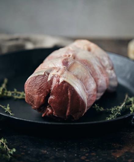 Wild venison loin roast in a cast-iron pan with thyme