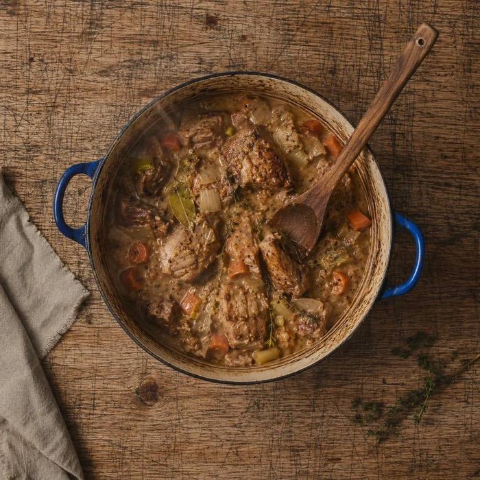 Rustic pork, cider and mustard casserole in a blue casserole dish